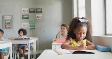 Sınıfta ders sırasında masasında oturan Afrikalı Amerikalı bir kızın videosu. İlkokul eğitimi ve öğrenme kavramı.