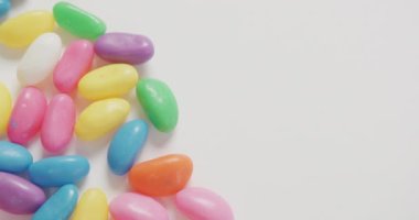 Beyaz zemin üzerinde fotokopi alanı olan çok renkli şekerlerin yakın çekim videosu. Füzyon yiyecek ve tatlı konsepti.