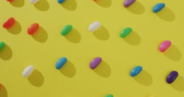 Sarı arkaplan üzerindeki çok renkli tatlı sıralarının genel görünüm videosu. Füzyon yiyecek ve tatlı konsepti.