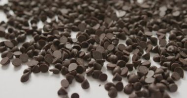 Beyaz arka plan üzerinde çoklu çikolata parçacıklarının yakın çekim videosu. Füzyon yiyeceği, çikolata ve tatlı konsepti.