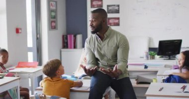 Çeşitli öğrencilerle ders sırasında mutlu Afrika kökenli Amerikalı erkek öğretmenin videosu. İlkokul eğitimi ve öğretmenlik mesleği.