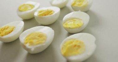 Gri arka planda kaynamış yumurtaların yarısının yakın çekim videosu. Füzyon yiyeceği, pişirme, yumurta ve paskalya konsepti.