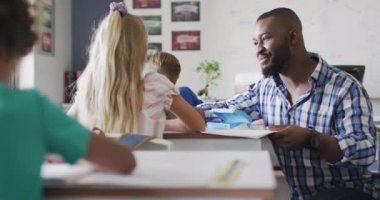 Afrika kökenli Amerikalı erkek öğretmenin beyaz bir kızla el çırpışının videosu. İlkokul eğitimi ve öğretmenlik mesleği.