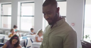 Farklı sınıftan öğrencileri olan mutlu bir Afrikalı Amerikalı erkek öğretmenin videosu. İlkokul eğitimi ve öğretmenlik mesleği.