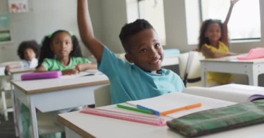 Mutlu Afrikalı Amerikalı çocuğun ders sırasında el kaldırdığı bir video. İlkokul eğitimi ve öğrenme kavramı.