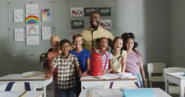 Dersler sırasında farklı sınıflardan öğrencileri olan mutlu bir Afrikalı Amerikan öğretmeninin videosu. İlkokul eğitimi ve öğretmenlik mesleği.