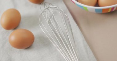 Bej arka planda kırsal kumaş üzerinde yumurta çırpma ve yumurta çırpma görüntüsü. Füzyon yiyeceği, pişirme, yumurta ve paskalya konsepti.