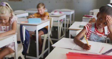 Sınıfta masasında oturan düşünceli Afrikalı Amerikalı kızın videosu. İlkokul eğitimi ve öğrenme kavramı.