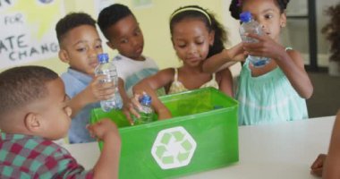 Sınıfta geri dönüşüm için plastik şişe sıralayan mutlu Afrikalı Amerikalı öğrencilerin videosu. İlkokul eğitimi ve öğrenme kavramı.