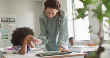 Kafkasyalı mutlu kadın öğretmenin Afrikalı Amerikalı çocuğa ders açıklarken ki videosu. okul eğitimi ve öğretmenlik mesleği.