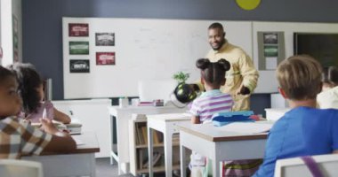 Dersler sırasında farklı sınıflardan öğrencileri olan mutlu bir Afrikalı Amerikan öğretmeninin videosu. İlkokul eğitimi ve öğretmenlik mesleği.