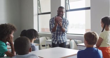 Biyoloji dersi sırasında mutlu Afrika kökenli Amerikalı erkek öğretmen ve çeşitli öğrencilerin videosu. İlkokul eğitimi ve öğretmenlik mesleği.