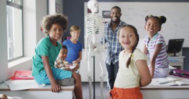 Anatomi dersi sırasında farklı sınıflardan öğrencileri olan mutlu bir Afrikalı Amerikan öğretmeninin videosu. İlkokul eğitimi ve öğretmenlik mesleği.