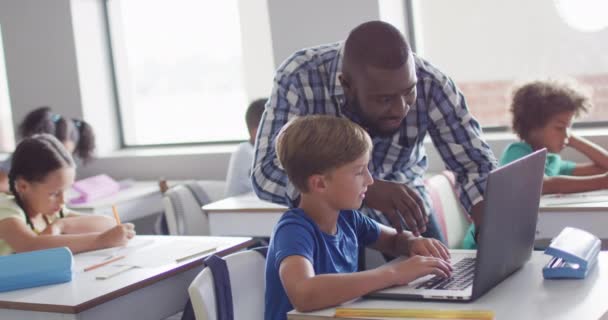 Відео Щасливого Афроамериканського Вчителя Чоловіка Який Допомагає Білоруському Хлопчику Ноутбуком — стокове відео