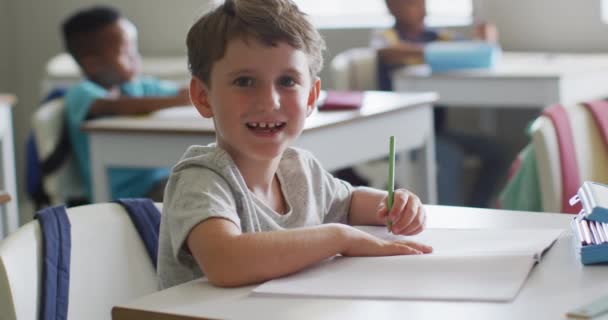 Video Lykkelig Gutt Som Sitter Ved Skrivebordet Leksjonen Klasserommet Grunnskoleutdanning – stockvideo