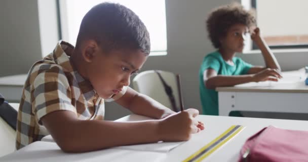 教室の机の上に座っている焦点を当てた出産少年のビデオ 小学校教育と学習の概念 — ストック動画