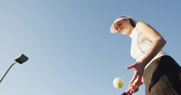 焦点を当てた白人女性テニス選手の低角度のビデオラケットを保持し ボールを打つ プロテニストレーニングスポーツ競技のコンセプト — ストック動画