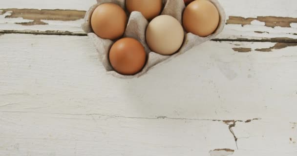 素朴な背景に卵カートンで茶色の卵のオーバーヘッドビューのビデオ 融合食品 ベーキング 卵とイースターの概念 — ストック動画