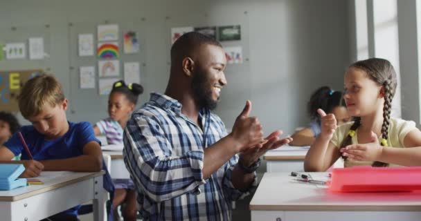 幸せなアフリカ系アメリカ人の教師のビデオ教室でカウントする方法を白人の女の子を学ぶ 小学校教育と教育の専門職 — ストック動画