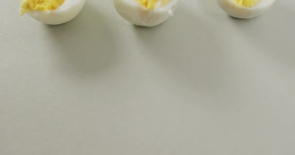 灰色の背景に硬いゆで卵の3つの半分のクローズアップのビデオ 融合食品 ベーキング 卵とイースターの概念 — ストック動画