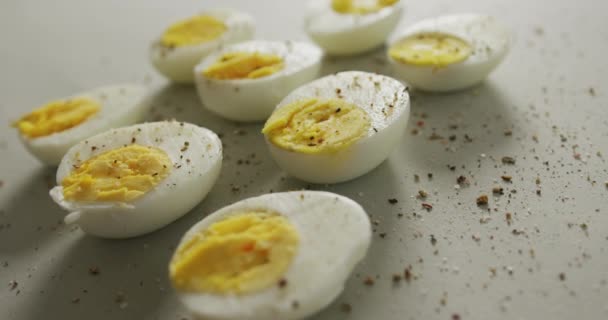 灰色の背景にハードゆで卵の半分の唐辛子のクローズアップのビデオ 融合食品 ベーキング 卵とイースターの概念 — ストック動画