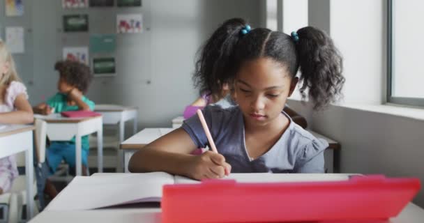 Video Focused Biracial Girl Sitting Desk Classroom Primary School Education — Vídeos de Stock