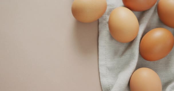 卵のオーバーヘッドビューとベージュの背景に素朴な布のビデオ 融合食品 ベーキング 卵とイースターの概念 — ストック動画