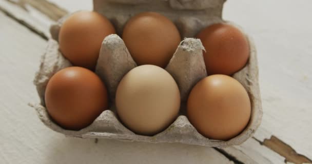素朴な背景に卵カートンで茶色の卵のオーバーヘッドビューのビデオ 融合食品 ベーキング 卵とイースターの概念 — ストック動画