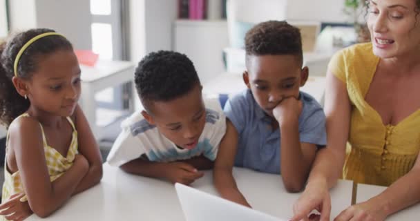 用笔记本电脑拍摄快乐的高加索女教师和非洲裔美国学生的视频 小学教育和教学专业 — 图库视频影像