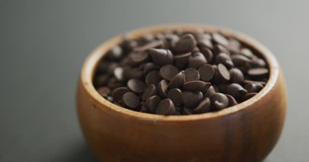 在灰色背景下的木碗巧克力片的特写视频 融合食品 巧克力和糖果的概念 — 图库视频影像