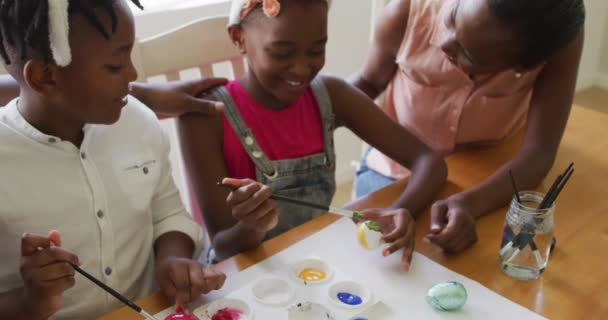 アフリカ系アメリカ人の家庭でイースターエッグを一緒に描いています イースター休暇の精神と喜びの概念 — ストック動画