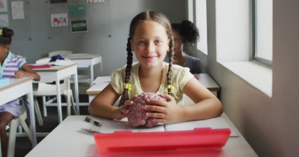ビデオ生物学の授業中に脳モデルを持っている幸せな白人の女の子 小学校教育と学習の概念 — ストック動画
