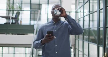 Ofiste akıllı telefon kullanan mutlu Afro-Amerikan iş adamı. Yaratıcı bir şirkette çalışıyorum..
