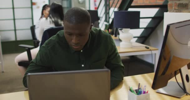 オフィスでノートパソコンを使っているアフリカ系アメリカ人のビジネスマン クリエイティブ ビジネスのオフィスで働いています — ストック動画