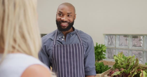 Vídeo Vendedor Americano Africano Feliz Mostrando Vegetais Orgânicos Para Cliente — Vídeo de Stock