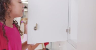 Okulun dolaplarını açan mutlu kızların videosu. İlköğretim, öğrenme ve sosyalleştirme kavramı.