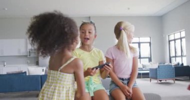 İlkokul eğitimi, öğrenme ve sosyalleşme kavramı. Okulun ortak salonunda oturan, akıllı telefonlu, konuşan ve gülen farklı kızların videoları..