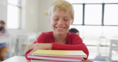 Okul masasında oturan mutlu beyaz çocuğun videosu. ilköğretim, bilgi ve öğrenme kavramı.