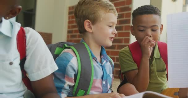 Видео Счастливых Разнообразных Мальчиков Держащих Книги Говорящих Перед Школой Начальное — стоковое видео