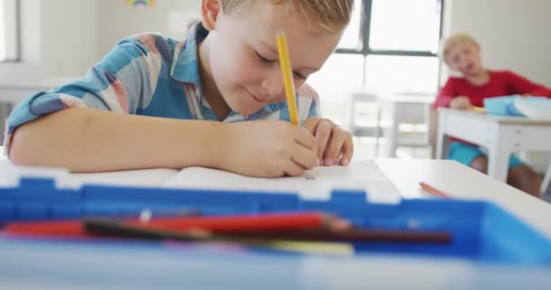 一个快乐的高加索男孩坐在课桌前写作的视频 小学教育 知识和学习概念 — 图库视频影像