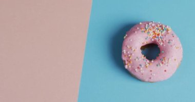 Mavi ve pembe arka planda kremalı donut videosu. Renkli yemek, şeker, abur cubur ve tatlı konsepti.