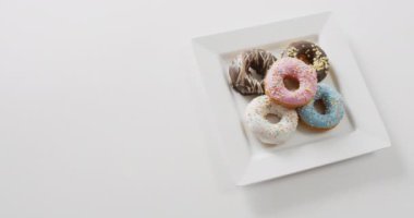 Beyaz arka planda kremalı donut videosu. Renkli yemek, şeker, abur cubur ve tatlı konsepti.