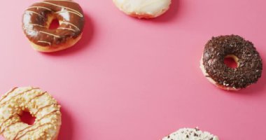 Pembe arka planda kremalı donut videosu. Renkli yemek, şeker, abur cubur ve tatlı konsepti.