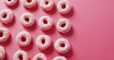 Pembe arka planda kremalı donut videosu. Renkli yemek, şeker, abur cubur ve tatlı konsepti.