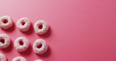 Pembe arka planda kremalı donut videosu. Renkli yemek, şeker, abur cubur ve tatlı konsepti.