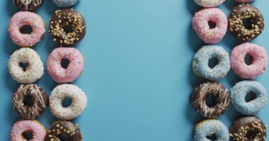 Mavi arka planda kremalı donut videosu. Renkli yemek, şeker, abur cubur ve tatlı konsepti.