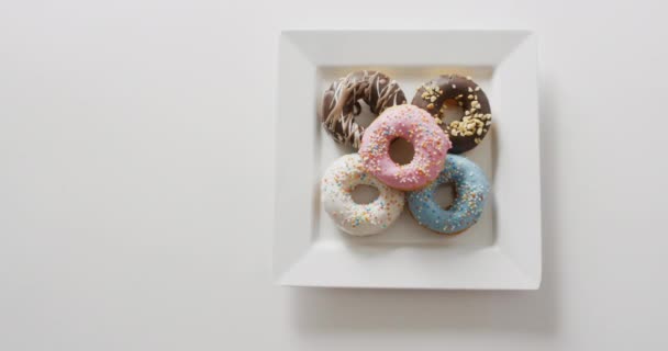 Vídeo Donuts Com Cobertura Placa Branca Sobre Fundo Branco Colorido — Vídeo de Stock