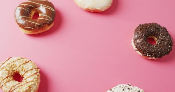 粉红背景上涂有糖霜的甜甜圈录像 五彩缤纷的食物 小吃和糖果概念 — 图库视频影像