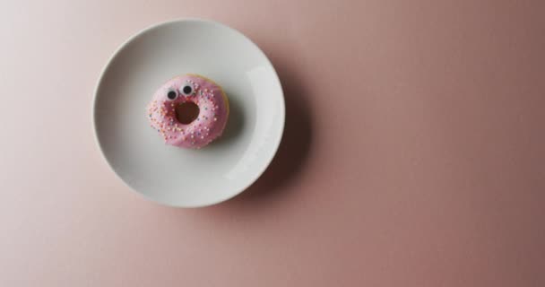 ピンクの背景に白いプレートにアイシングとドーナツのビデオ カラフルな楽しい食べ物 お菓子 お菓子のコンセプト — ストック動画