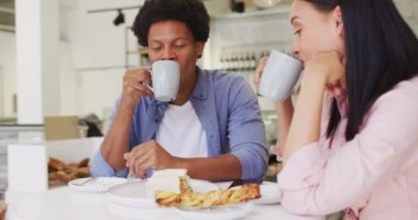 Video of happy diverse woman and man drinking and talking at coffee shop. coffee and bistro shop, running small independent business.